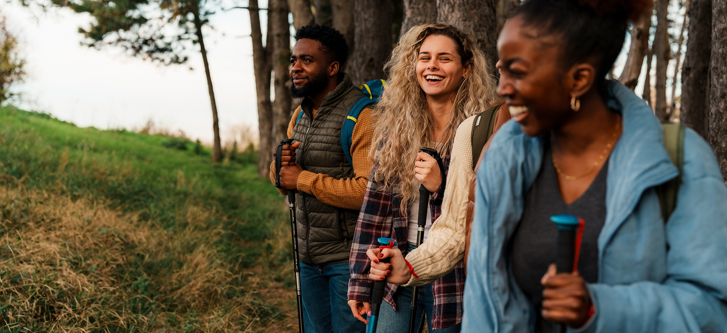 A group of friends smiling and laughing together while hiking through a forest