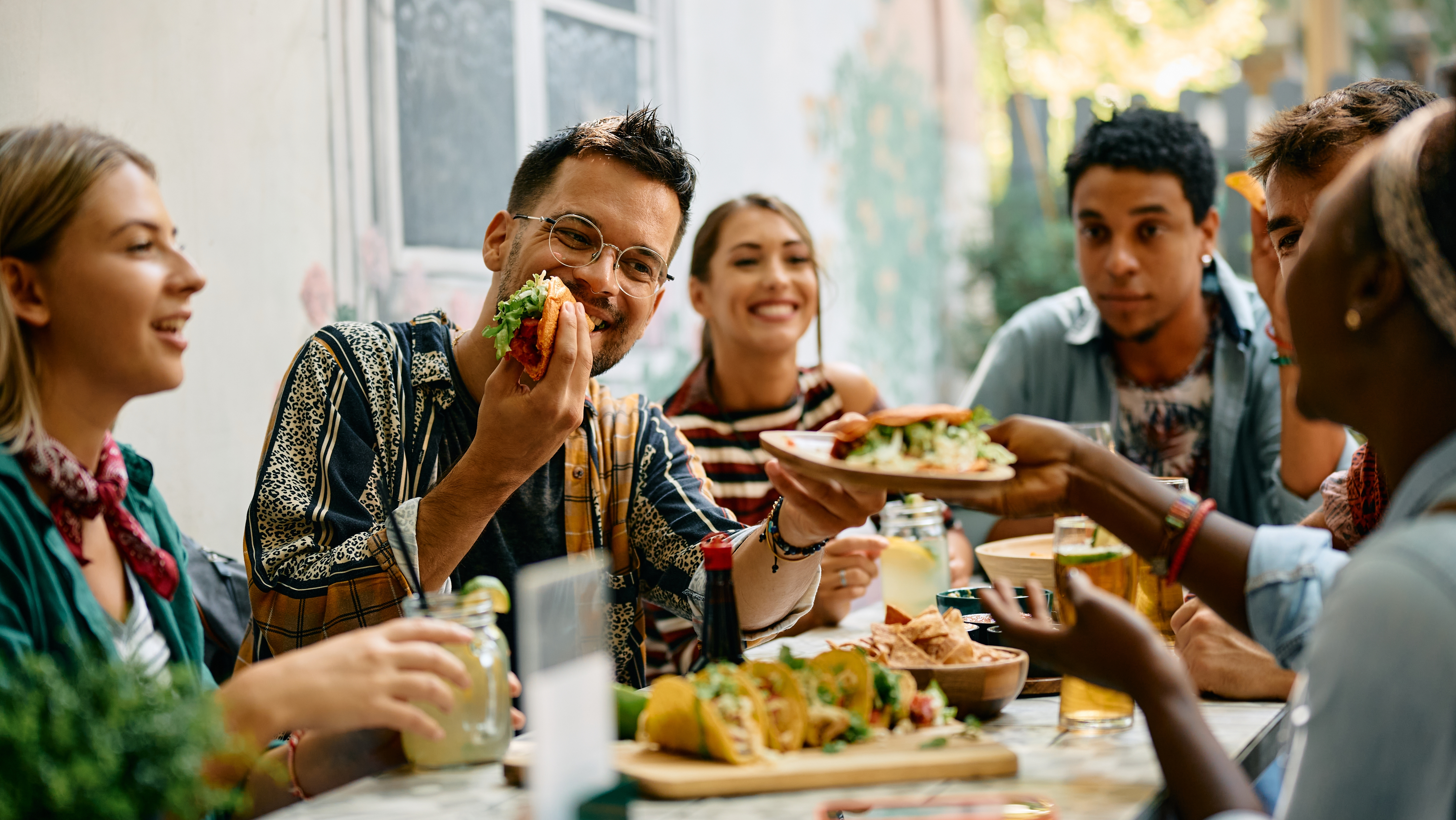 Group of friends having fun and eating tacos together on an outdoor
patio
